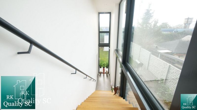 A staircase with large windows, overlooking the garden in a family house.