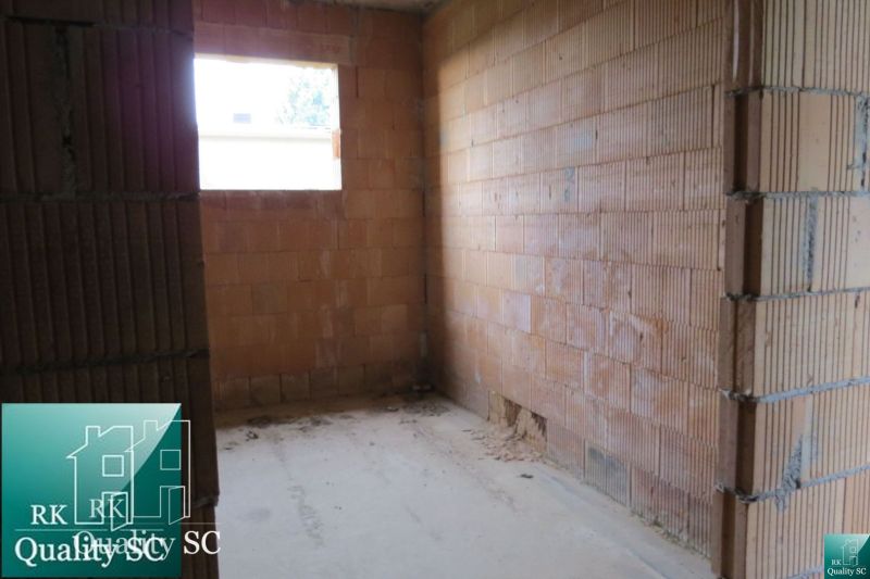 Unplastered brick walls in a room of a family house, with a window on the wall.