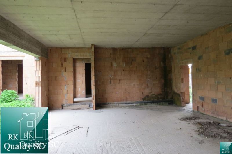 Unfinished interior in a family house with exposed brick walls and a concrete ceiling.