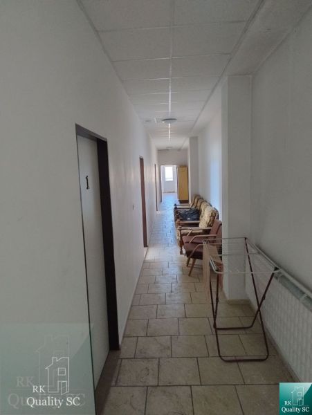 A corridor with a light floor, a ceiling with a soffit, chairs, and a clothes dryer in warehouses and halls.
