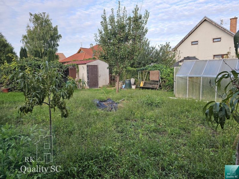 The garden of a family house in the village of Tureň with various trees and a greenhouse.