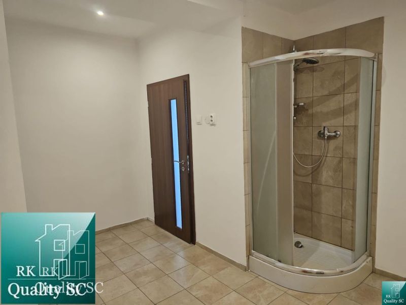 Interior of a commercial space with tiling and a shower corner.