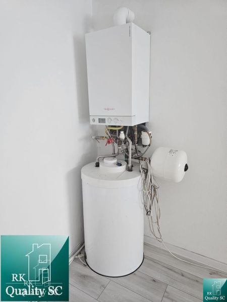 Boiler and water heater in the interior of commercial premises, with a wooden decor floor.