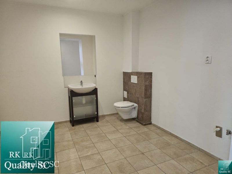 Bathroom with tiles, sink, and toilet in commercial premises.