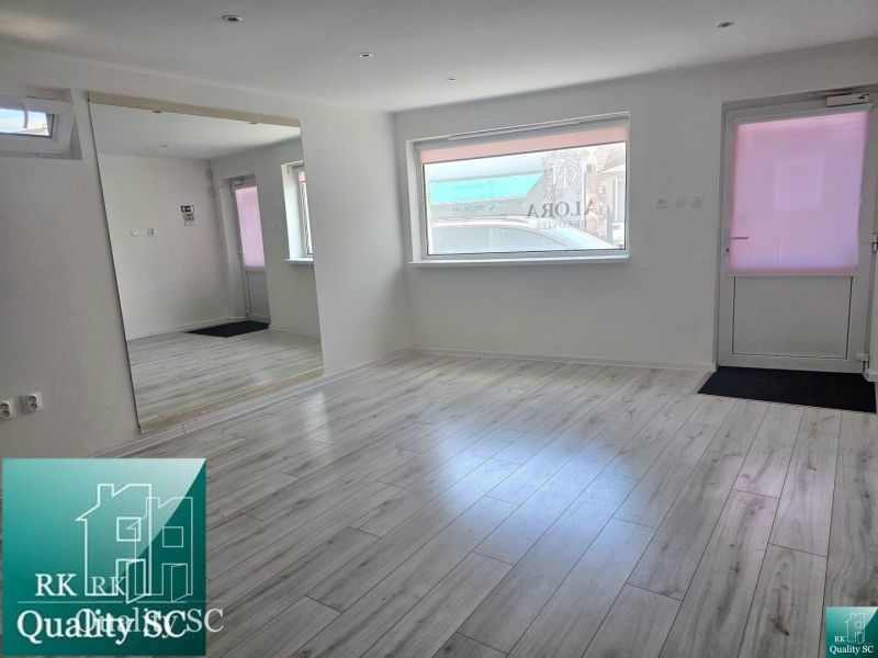 Commercial premises with a wooden decor floor, mirror, and windows.