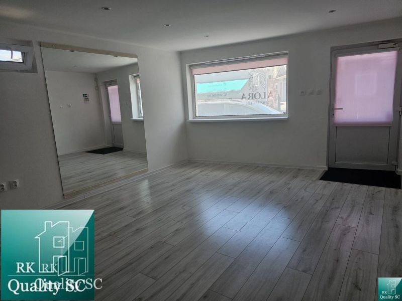 Bright commercial space with wood-patterned flooring and a large mirror.