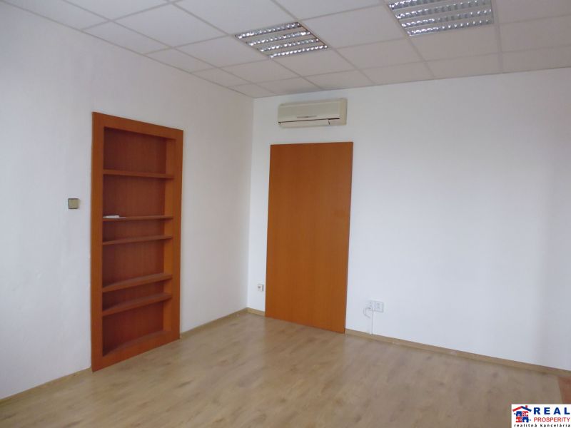 A space with white walls, a wooden decor floor, and a built-in shelf.