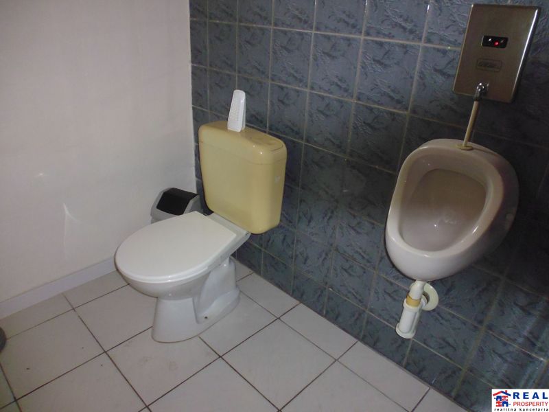 Restroom with a urinal in commercial premises with ceramic tiles and flooring.