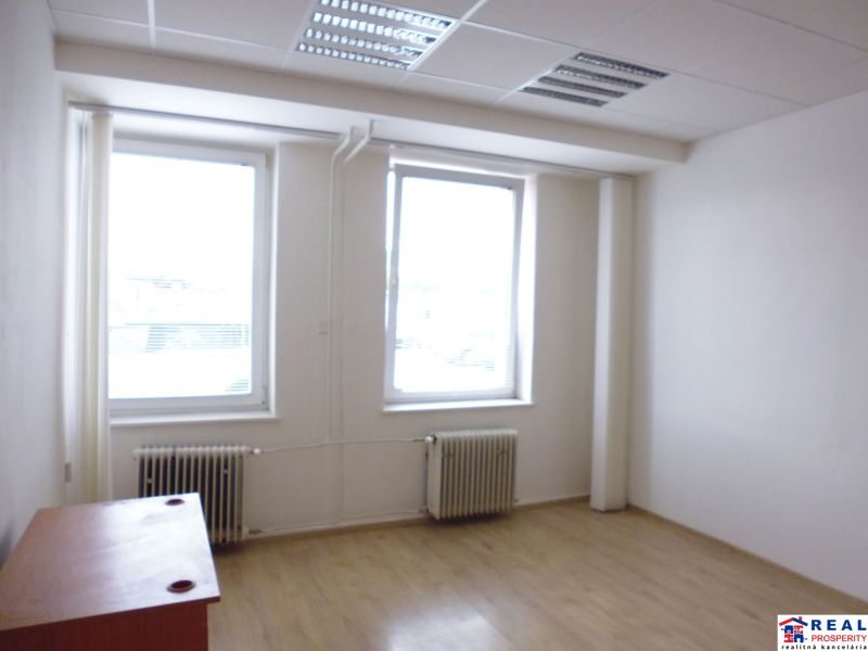 Commercial premises with two windows, radiators, and a floor with a wooden decor.