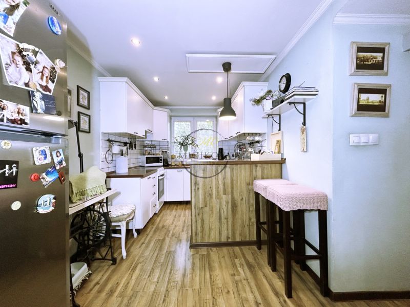 A kitchen in a 2-room apartment with a wooden decor floor and white cabinets.