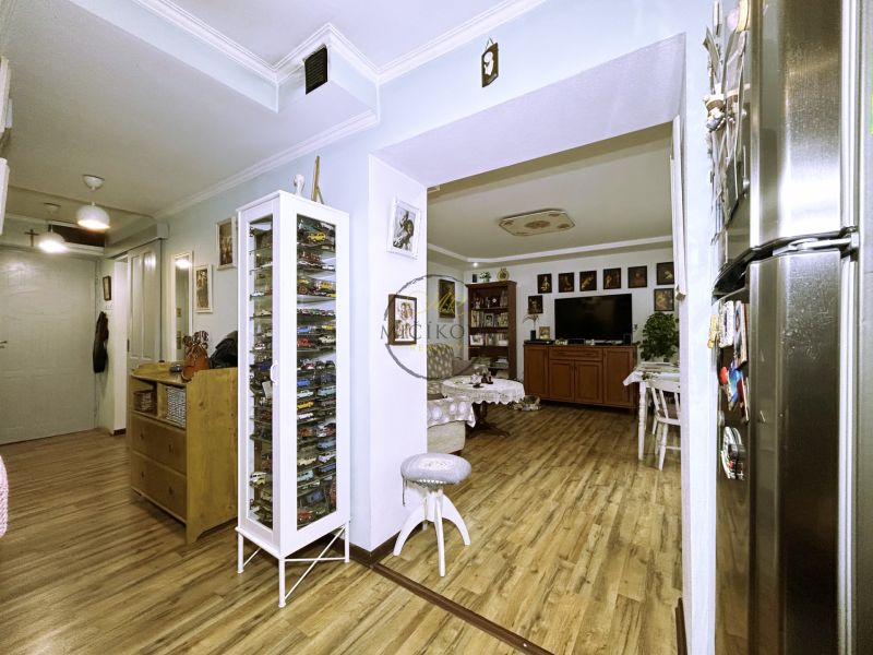 Interior of a 2-room apartment with a wooden decor floor and a showcase with model cars.