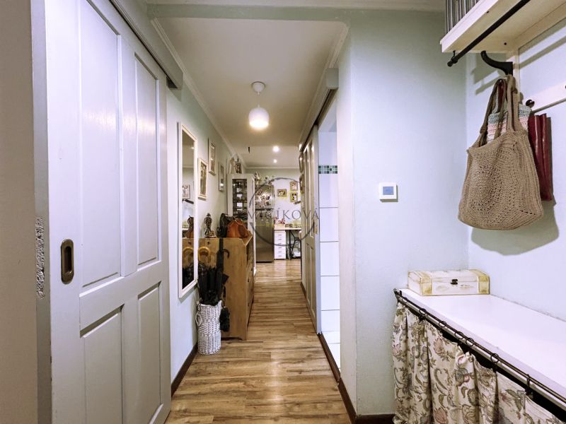 A hallway with a wooden decor floor in a 2-room apartment, with a coat rack wall and a cabinet.
