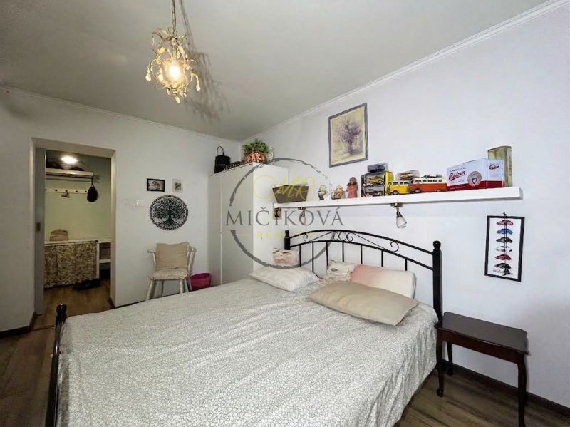 Bedroom in a 2-room apartment with a bed, decorations, and a floor with a wooden decor.
