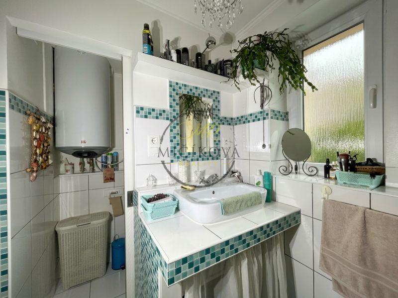 A bathroom in a 2-room apartment with white tiles and green decorations.