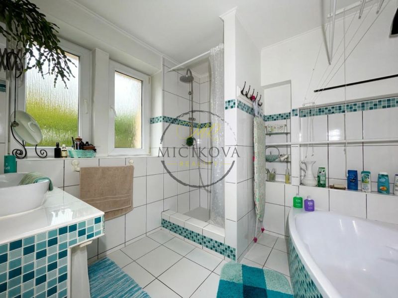 A bathroom in a 2-room apartment with a shower and a bathtub, tiled with mosaic tiles.