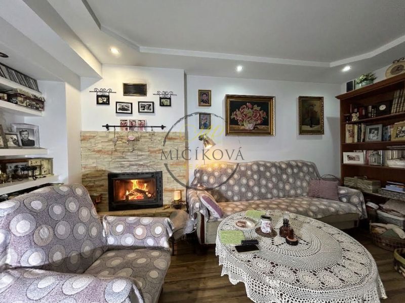 Living room in a two-room apartment with a fireplace, wall decor, and shelves.