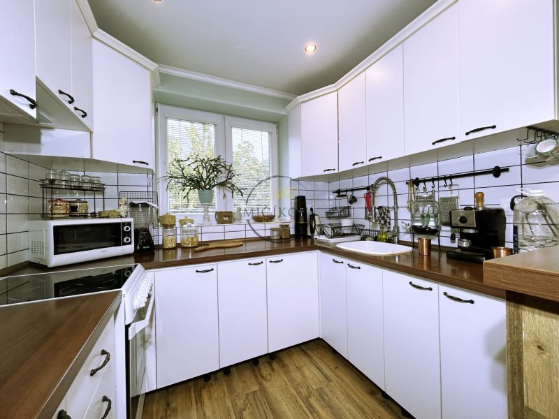 A kitchen in a 2-room apartment with white cabinets and a wood-patterned floor.