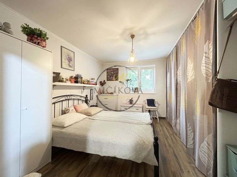 A bedroom in a two-room apartment with a wooden decor floor, curtains, and decorations.