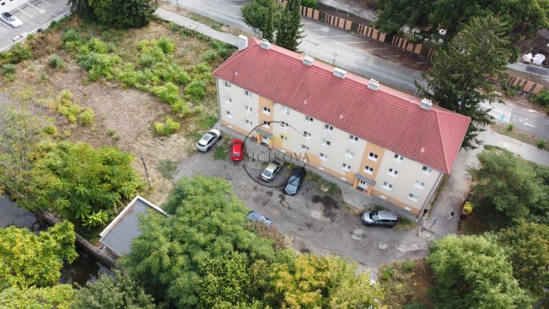 A building on Ľudovíta Štúra Street in Levice surrounded by greenery and a parking lot for cars.