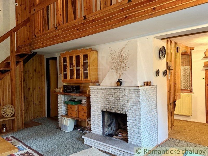 The interior of a cabin with a fireplace, wooden staircase, and floor with a wooden decor.