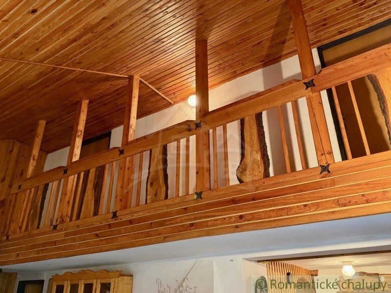 Wooden railing and ceiling with decor in the cottage create a cozy atmosphere.