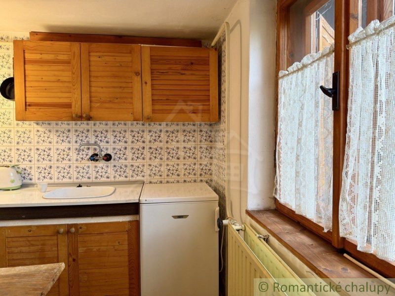 Rustic kitchen in a cottage with wooden decor and decorative tiles.