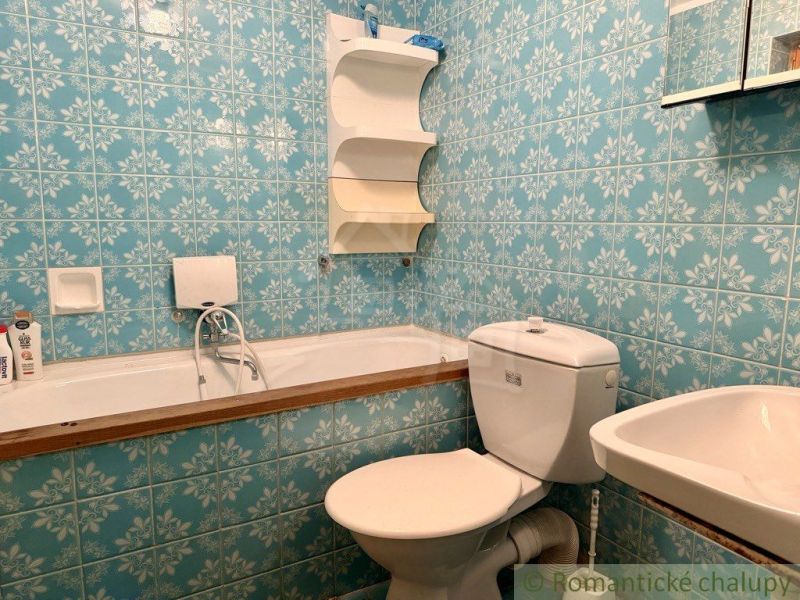 A bathroom with retro blue tiles, a sink, a bathtub, and a toilet in a cabin.