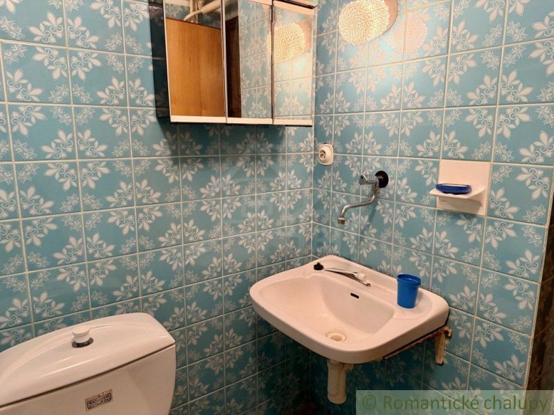 A bathroom with blue tiles, a sink, and a mirror on the wall.