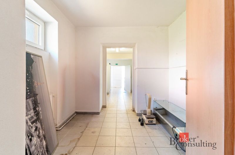 A corridor with white walls and tiles in commercial premises.
