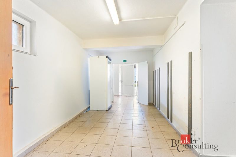 Hallway in commercial premises with white walls and ceramic flooring.