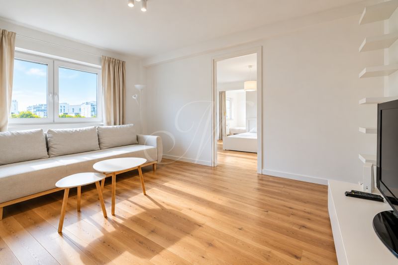 Living room in a 2-room apartment with a sofa, tables, and a floor with a wooden decor.