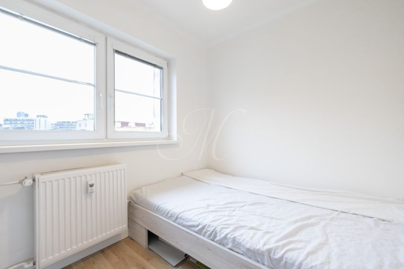 A bright bedroom with a bed and a window in a 2-room apartment.