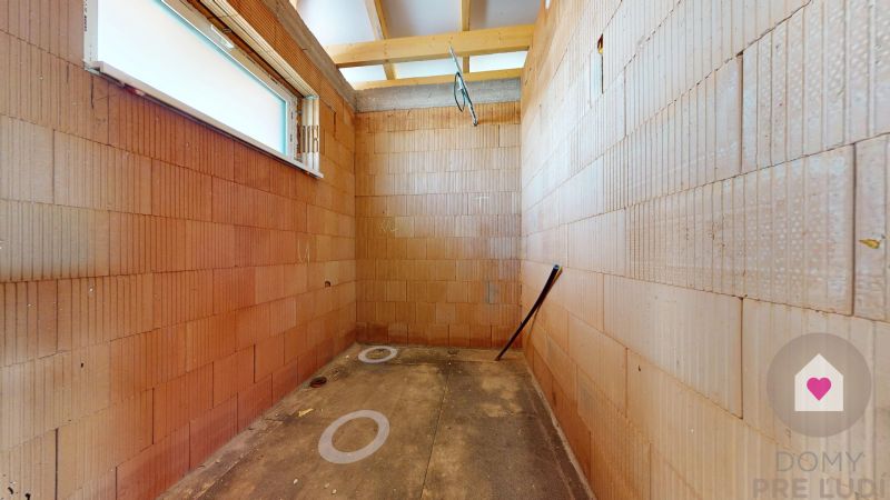 Unplastered bricks and a window in the interior of a family house awaiting completion.