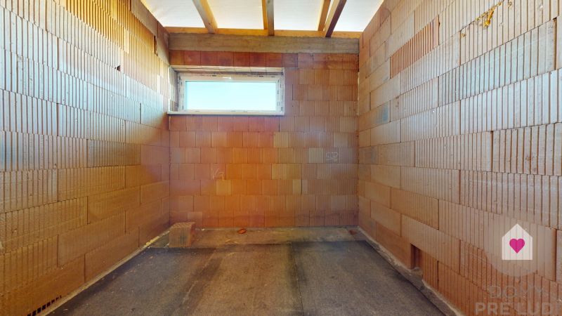 Unfinished room in a family house with brick walls and a small window.
