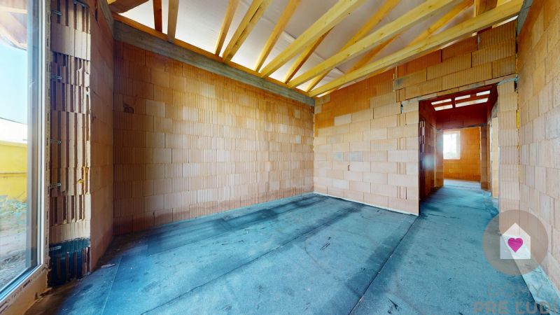 A room with bare brick walls and exposed rafters in a family house.