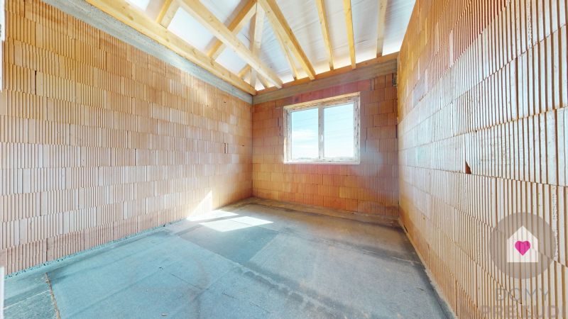 Unfinished interior of a family house with brick walls and a window.