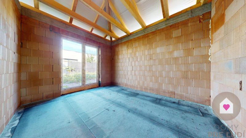 A room in a family house with raw brick walls and a window to the garden.