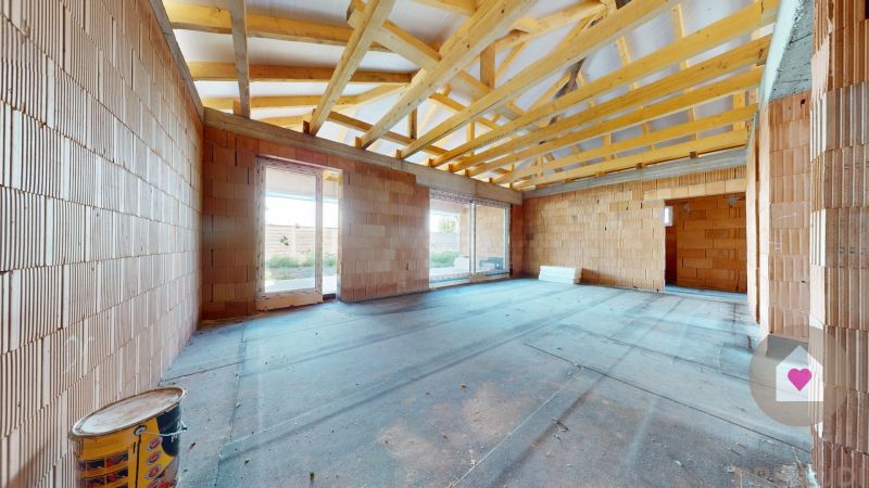 Unfinished room with brick walls in a family house with a wooden truss.