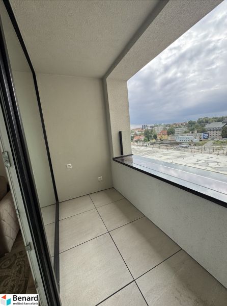 A balcony with tiles overlooking the city from a studio apartment.