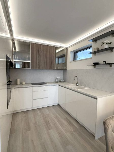 Kitchen in a 2-room apartment with white cabinets and a wood-patterned floor.
