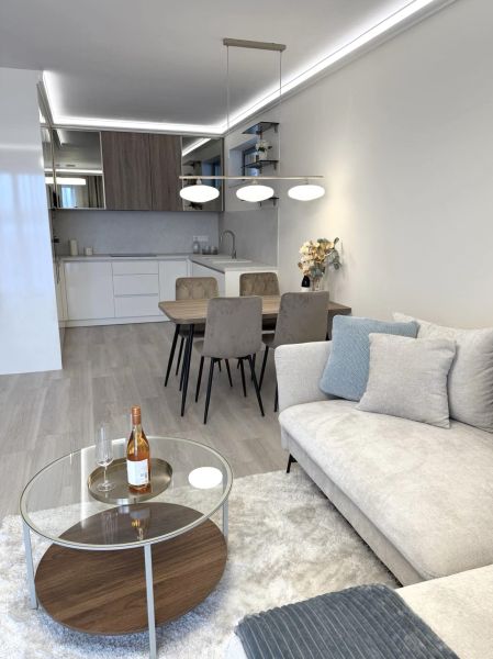 Living room in a two-room apartment with a wooden decor floor, sofa, and dining table.