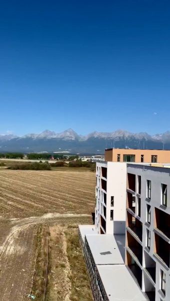 View of the mountains and a building from Suchoňova Street in Poprad, ideal for a 4-room apartment.