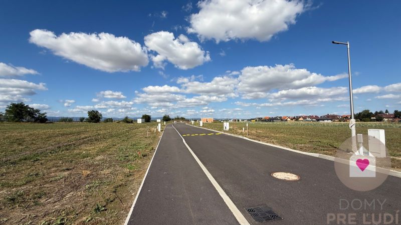 Nová Dedinka, Bernolákova, empty plot, flat road, blue sky, only a few houses.