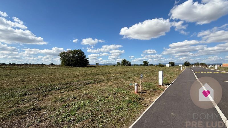 A vacant plot next to a family house on Bernolákova Street in Nová Dedinka with an asphalt road.
