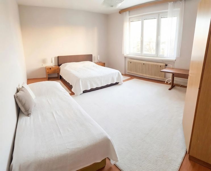 Bright bedroom interior in a family house with wood-decor flooring and comfortable beds.