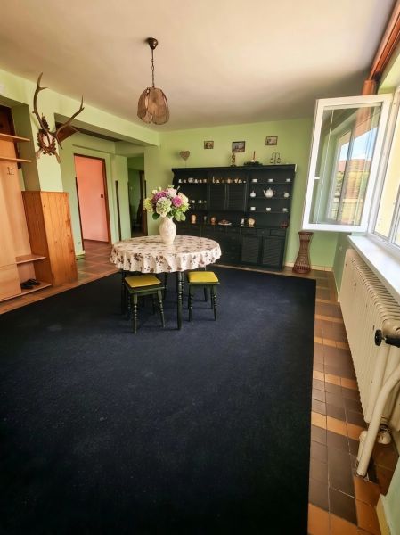 Living room in a family house with flowers on the table and an open window.