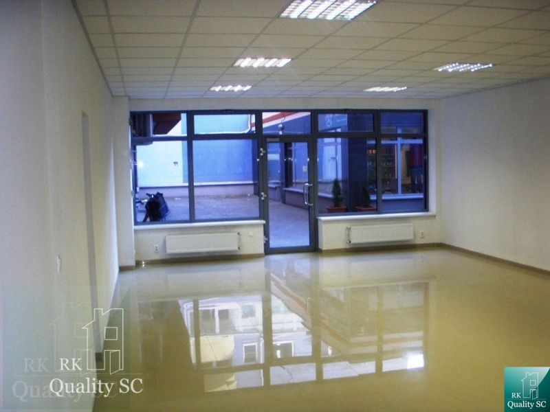Spacious offices with large windows and glossy wooden-patterned flooring.