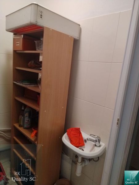 A small sink with a cabinet and cleaning products in the office.