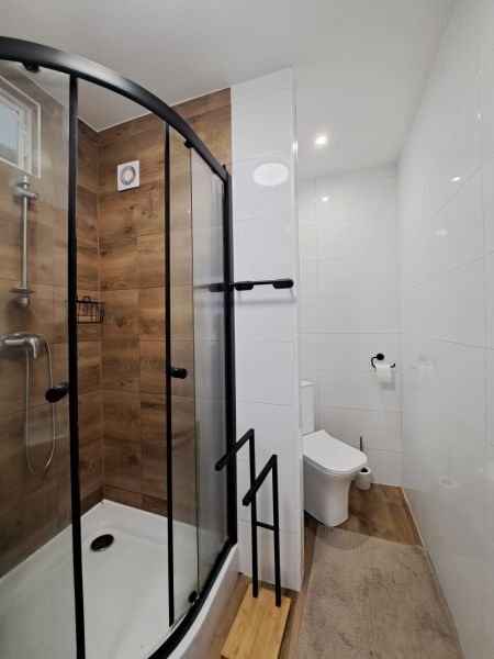 A bathroom with a shower and a floor with a wooden decor in a 3-room apartment.