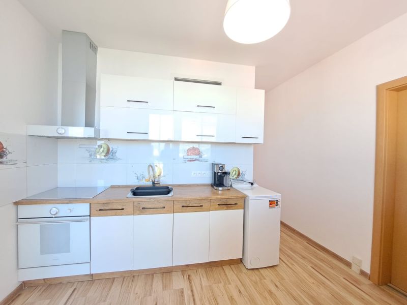 A kitchen in a 3-room apartment with white cabinets and a wooden decor floor.